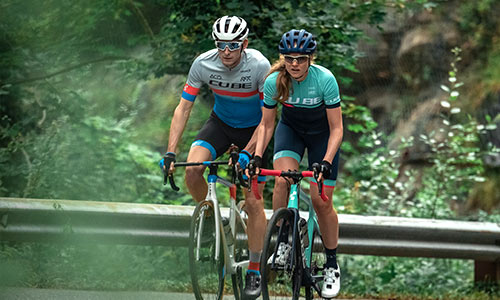 A man and a woman are riding cyclocross bikes on the road.
