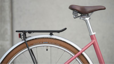 The image shows a close-up of the luggage rack and saddle of a Cube Ella hybrid e-bike.
