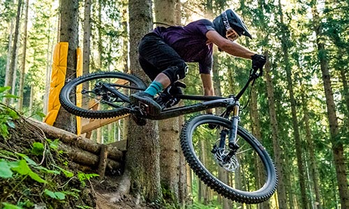 Cyclist jumps in the forest with a full-suspension mountain bike.